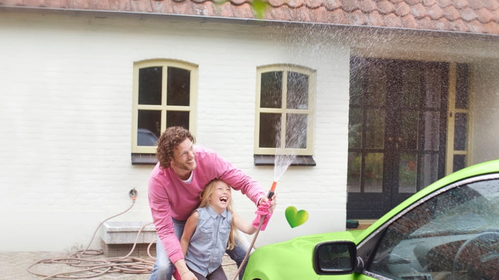 Father and daughter washing a green car